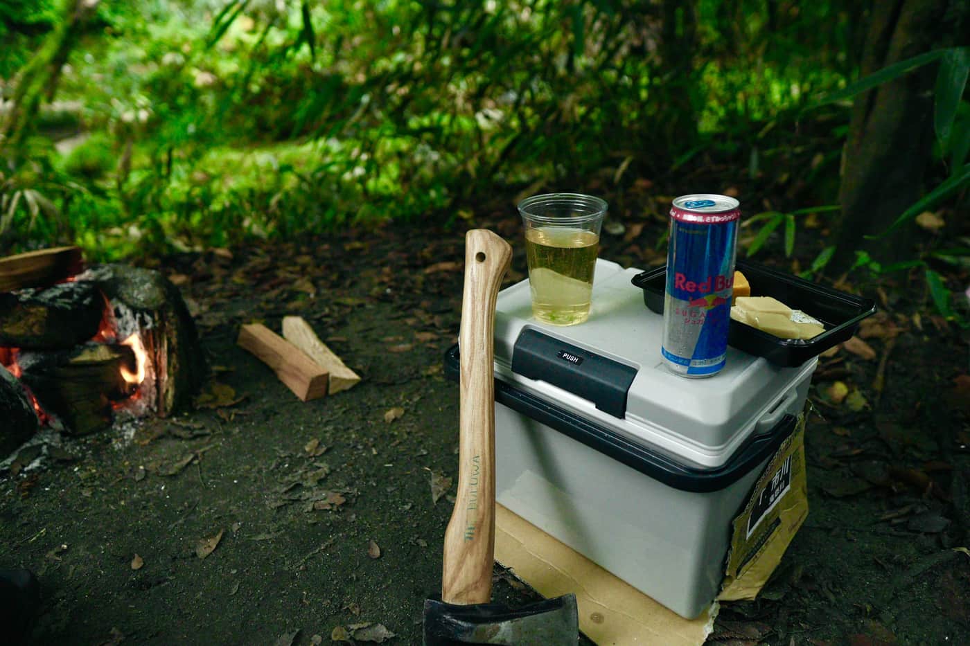 A cooler box and food set out at an outdoor campsite