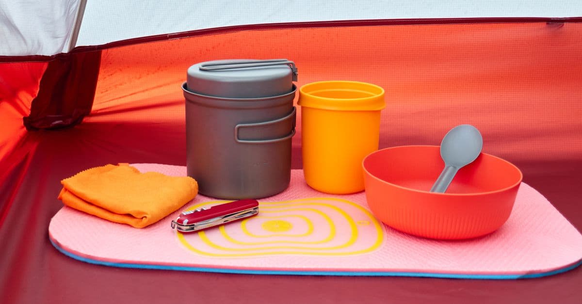 Compact camping cookware and gear arranged inside a tent
