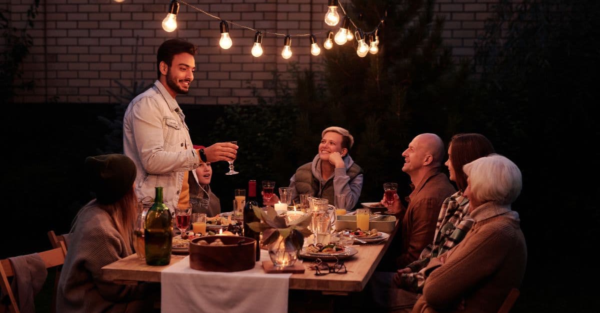 An outdoor dinner table lit by warm string lights after dark