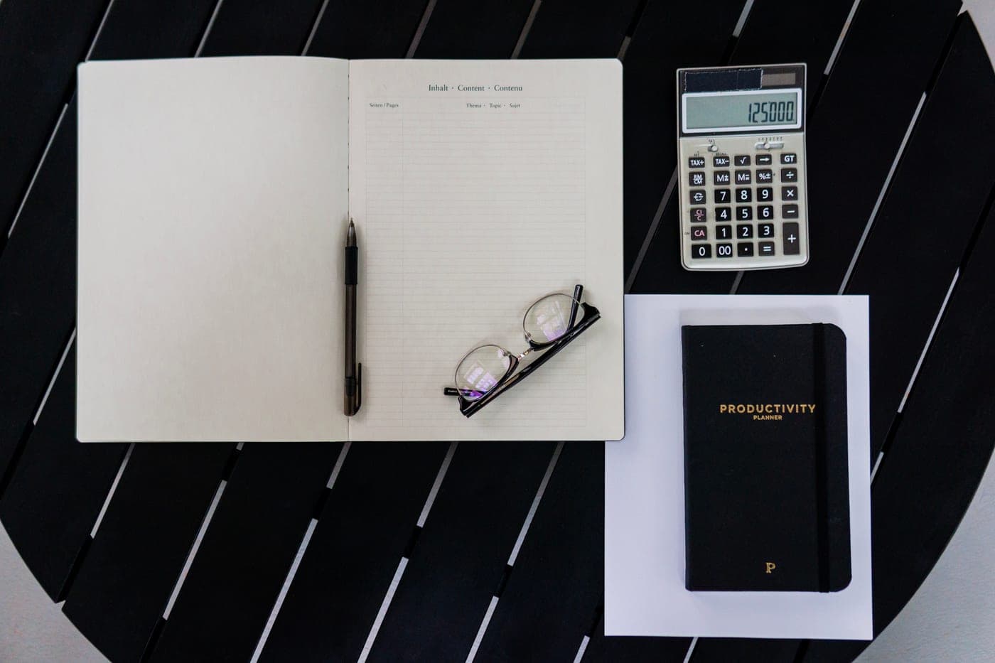A notebook, pen and calculator laid out on a desk