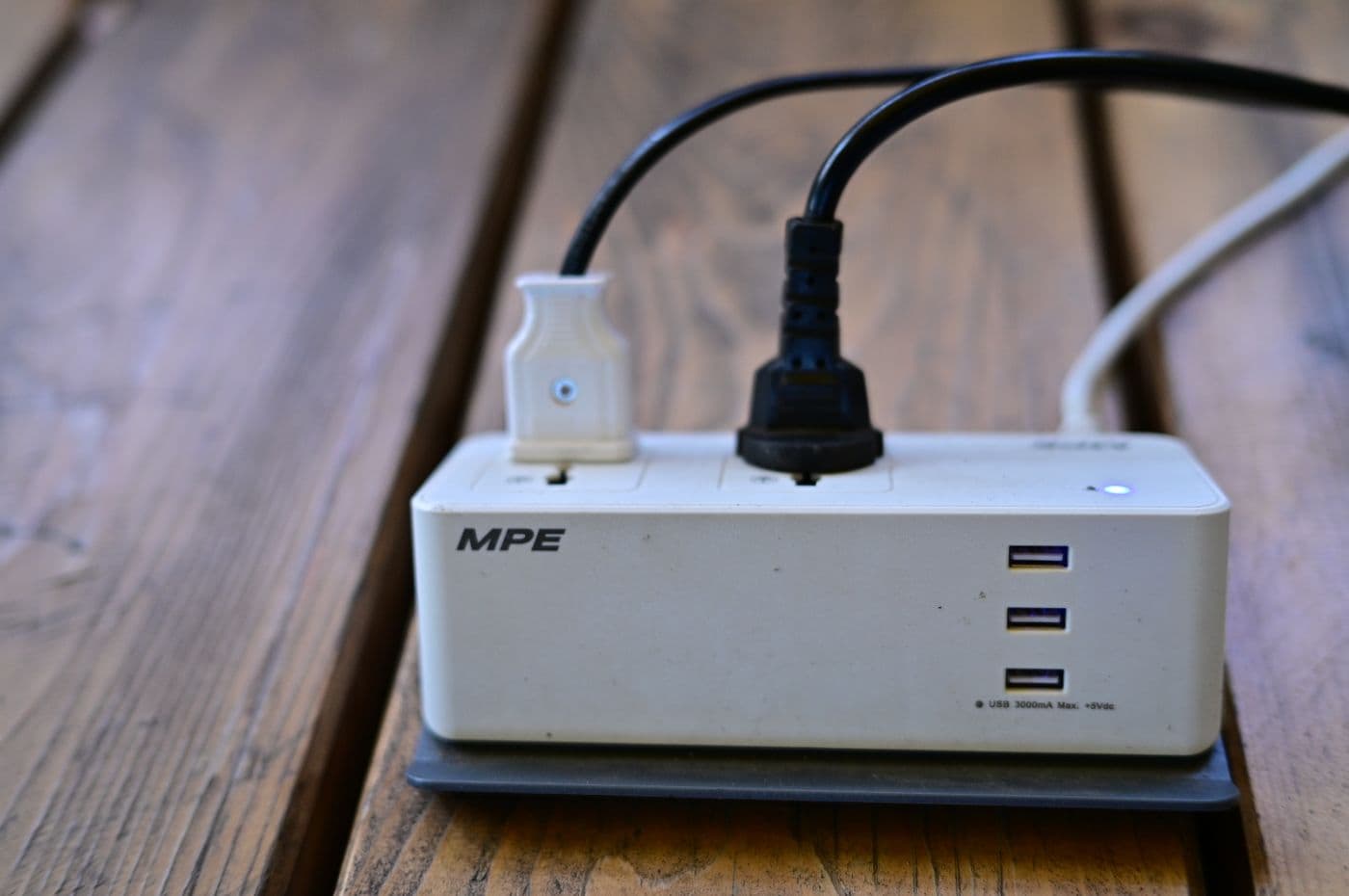 A power strip with several cables and USB ports connected on a wooden surface