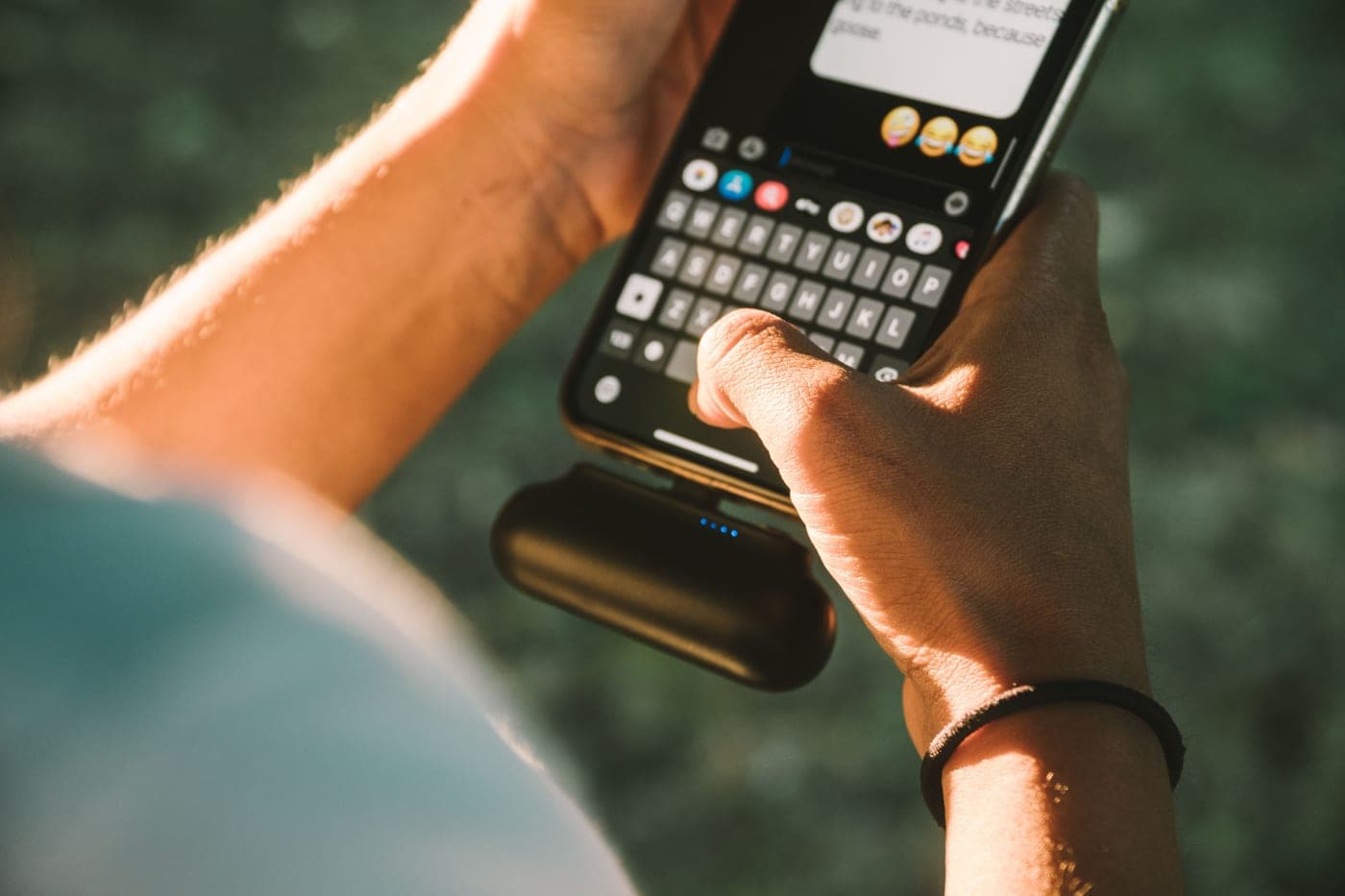 A hand holding a small battery pack charging a phone