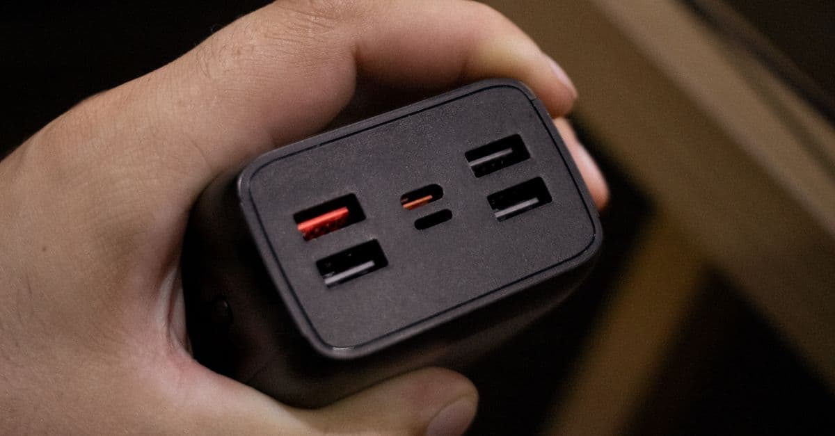 A hand holding a multi-port USB power adapter