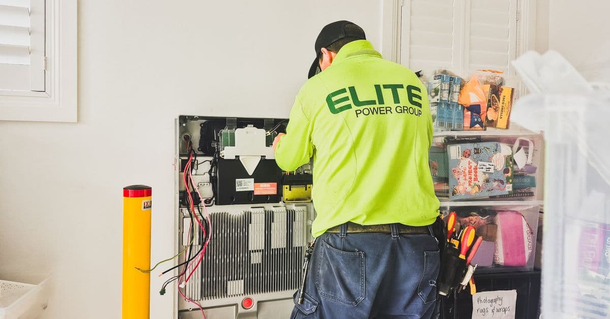 A technician installing a fixed home battery system indoors