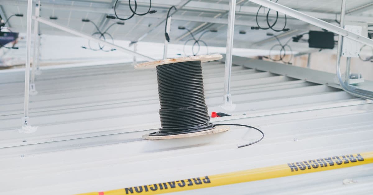 A coiled cable on a rooftop beside installed solar panels