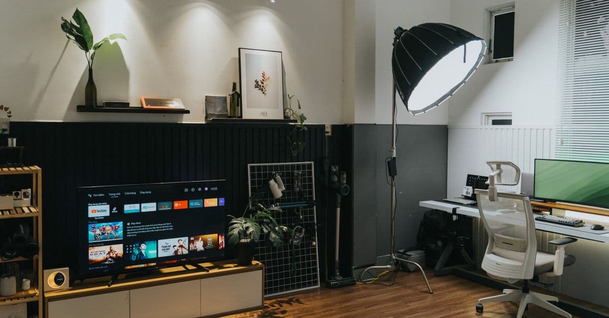 A dark living room with a wall-mounted television and modern furniture