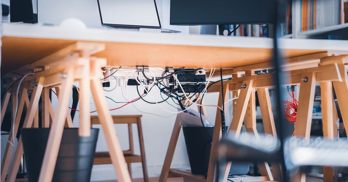 A desk workspace with a laptop, monitor and visible cabling