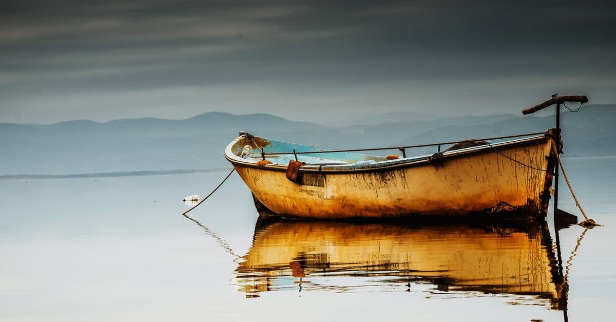 A small fishing boat reflected on calm water in the morning
