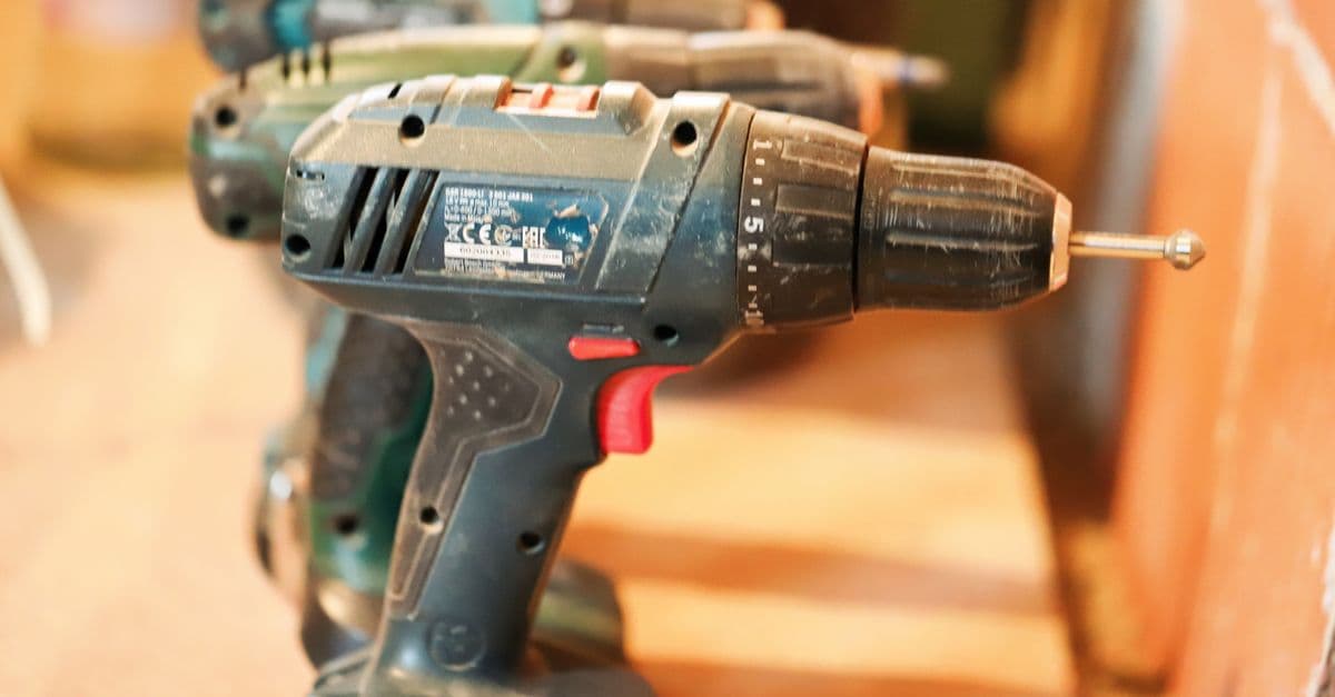 A row of cordless power drills on a wooden workbench