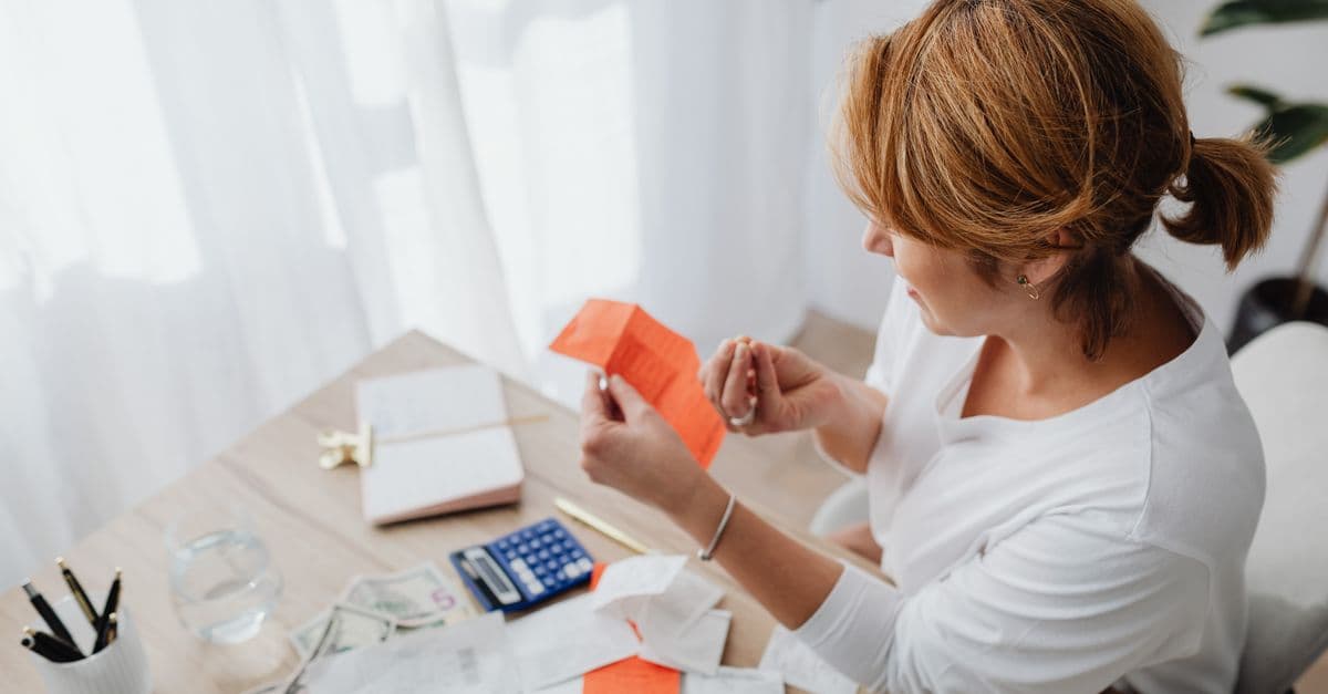 Someone working through bills and receipts at a desk with a calculator