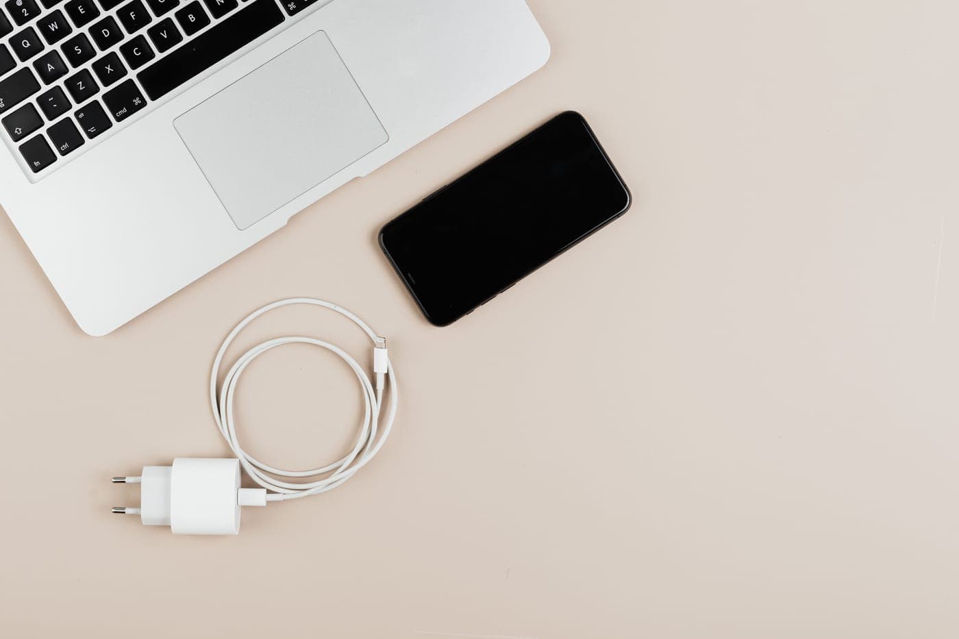 A laptop charging on a desk beside a coiled cable