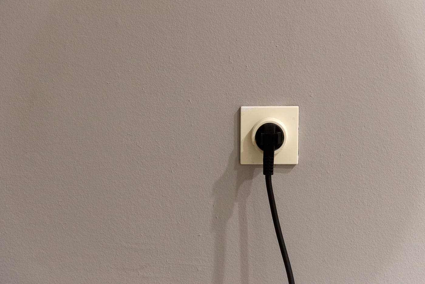 A power cable plugged into an outlet, photographed close up