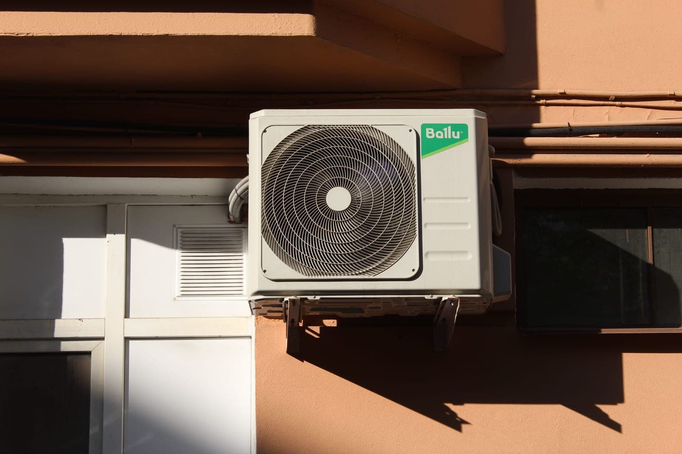 An air-conditioning condenser unit outdoors in summer