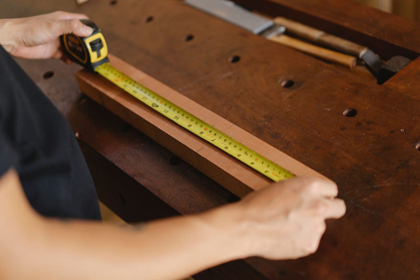 A tape measure and hand tools laid out on a workbench