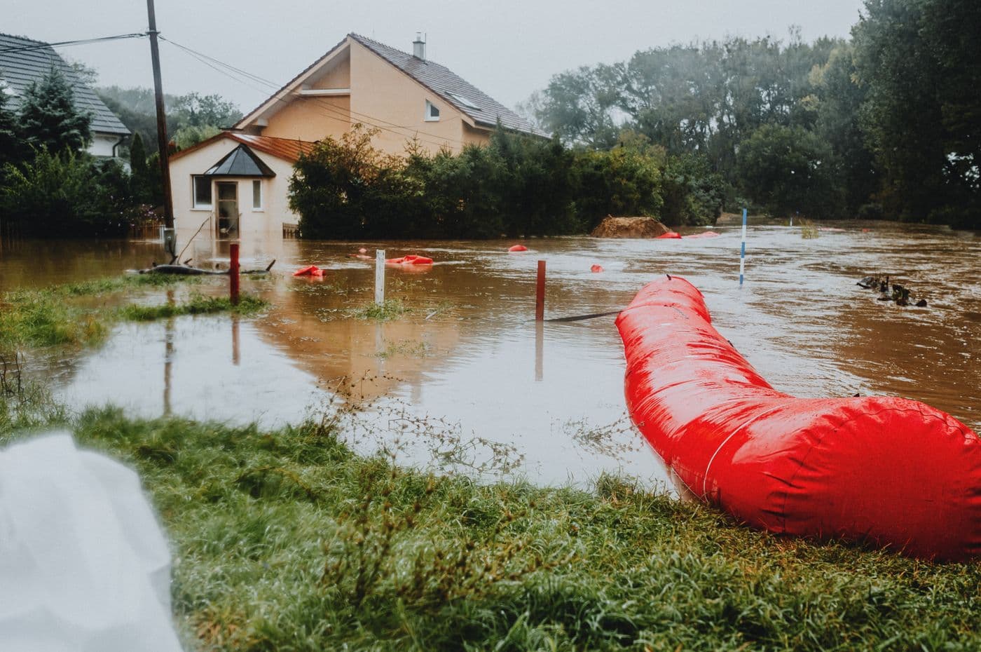 A flooded residential street held back by red flood barriers